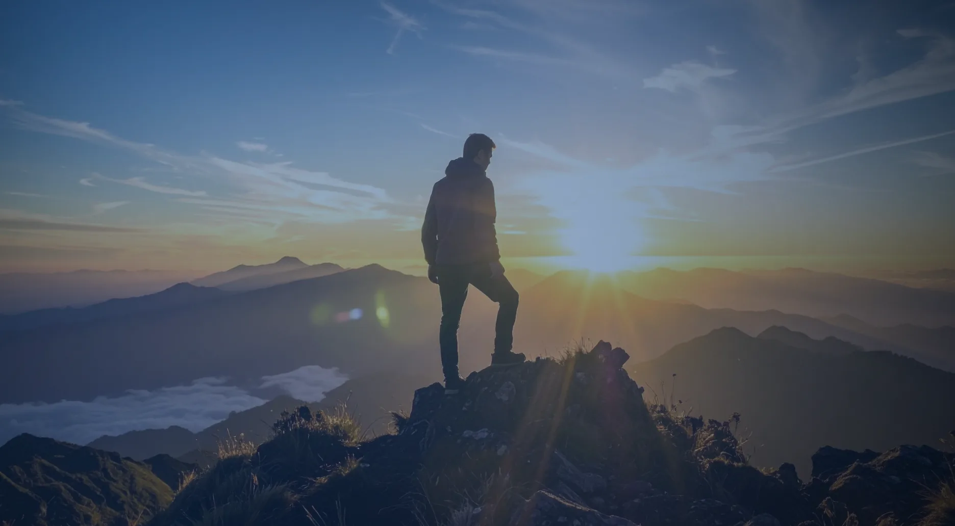 A hiker on a mountain summit at sunrise
